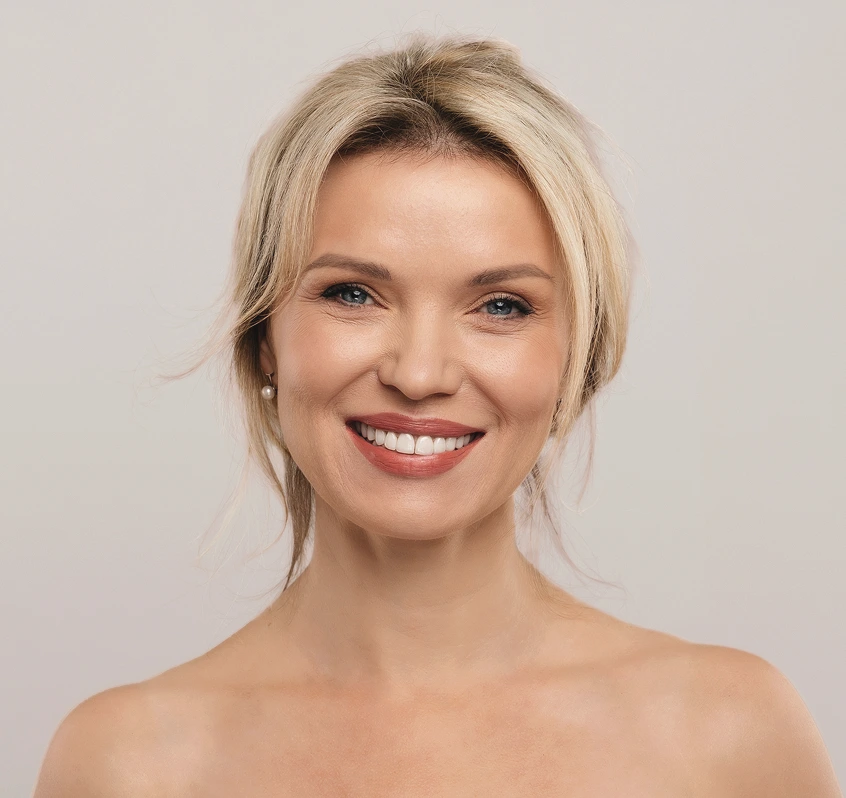 Woman with blonde hair smiling at camera against neutral background